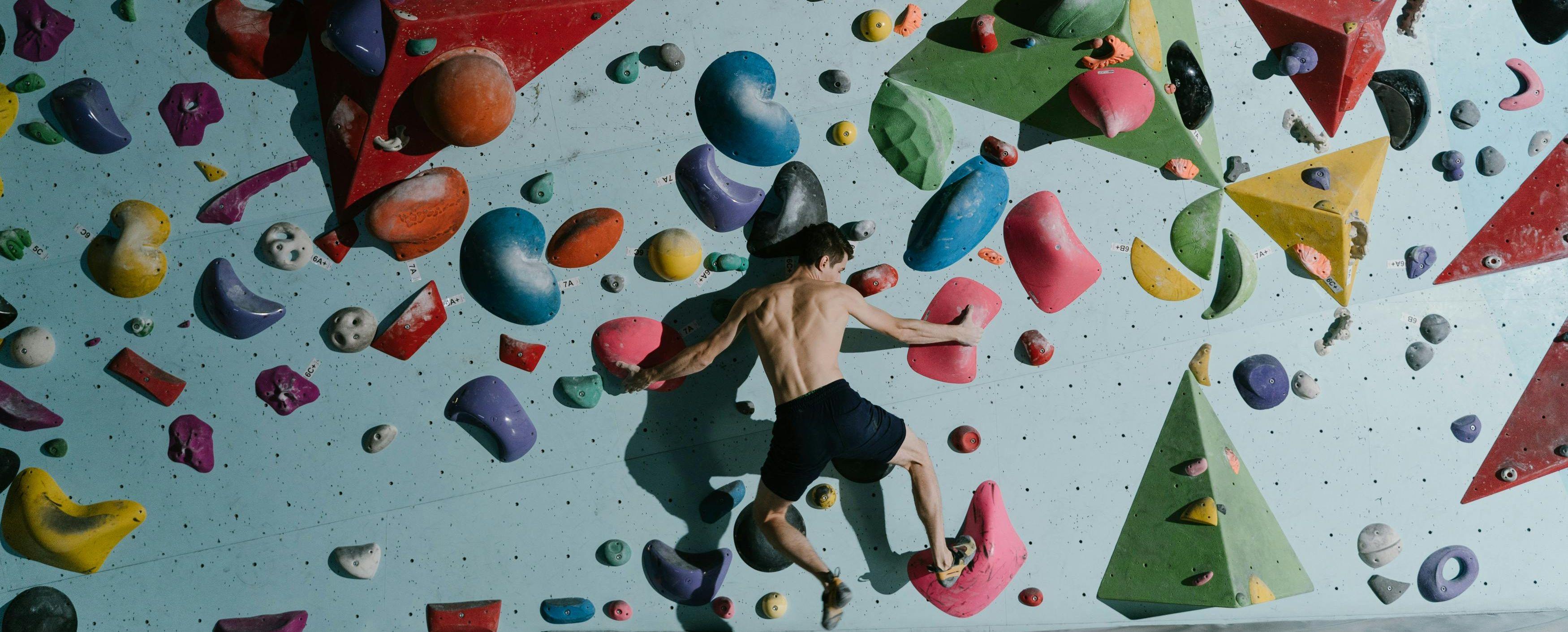 Mann klettert an einer Wand in einer Boulderhalle.